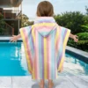 Toddler wearing a rainbow stripe hooded towel beside a swimming pool