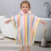Toddler wearing a colorful striped hooded poncho towel at home