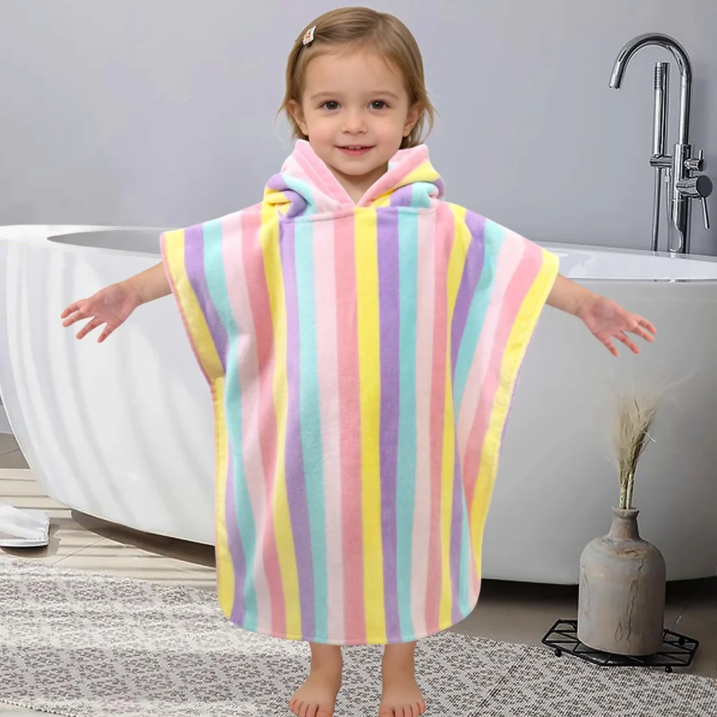 Toddler wearing a colorful striped hooded poncho towel at home