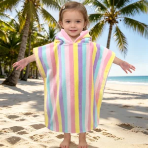 Toddler wearing a colorful rainbow stripe hooded towel at the beach